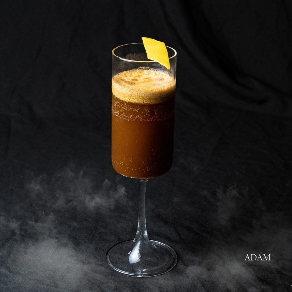 เครื่องดื่ม Adam กาแฟดำซิกเนเจอร์ของ Davin Cafe ในแก้วมีก้าน ตกแต่งด้วยเปลือกส้ม.