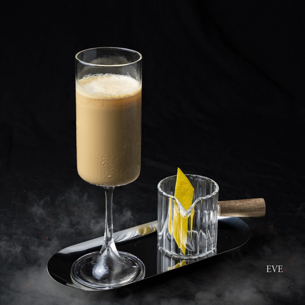 A glass of Eve, Davin Cafe's signature creamy drink, presented on a silver tray with a separate garnished glass.