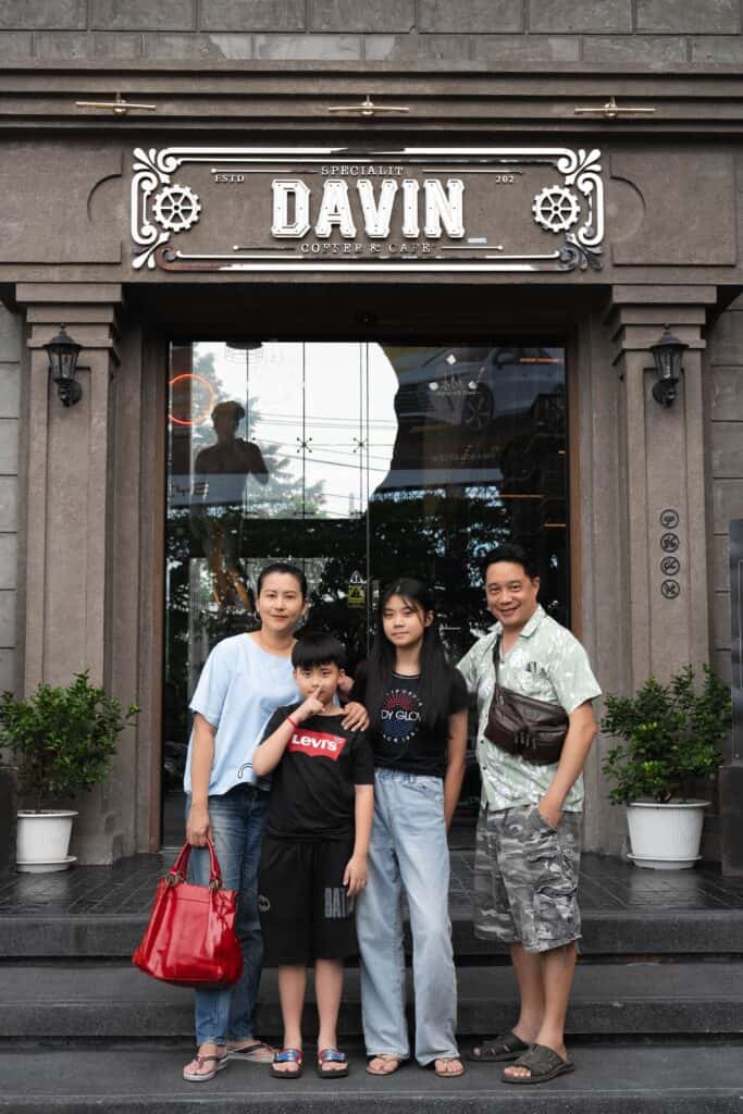 A family of four, including parents and children, posing for a photo outside the entrance of Davin Cafe.