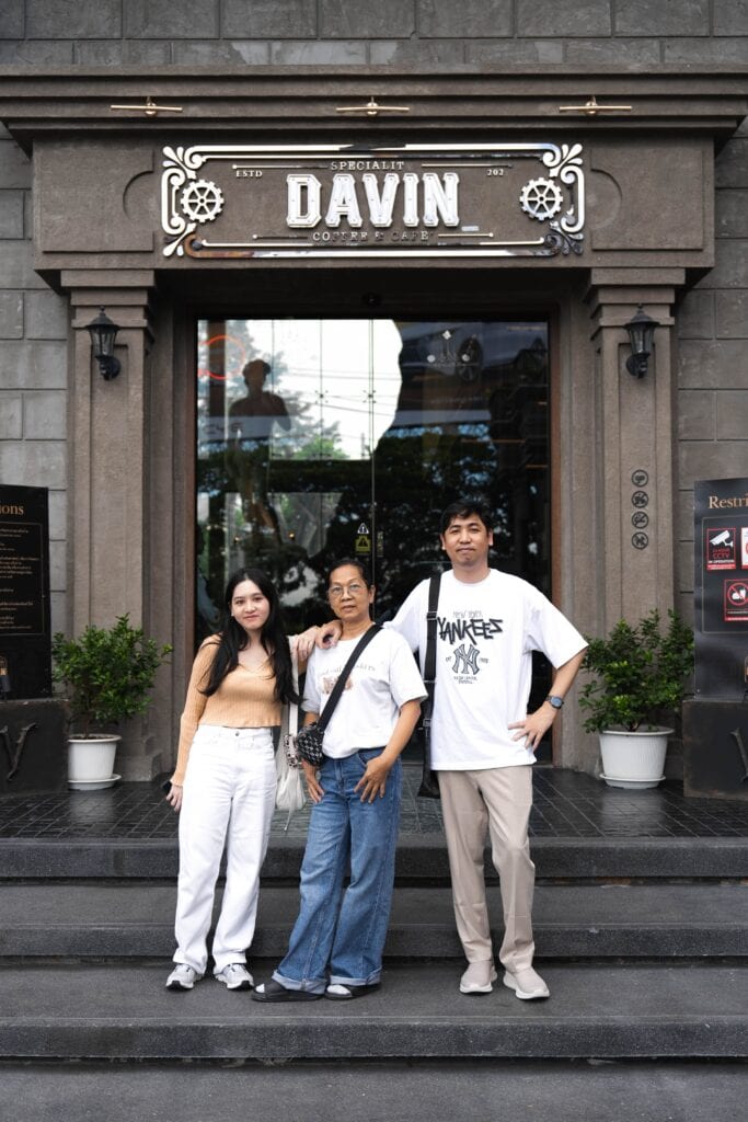 ภาพถ่ายครอบครัวสามคนกำลังยืนถ่ายรูปหน้าทางเข้าร้าน Davin Cafe.