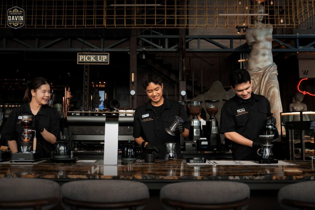 บาริสต้าสามคนกำลังร่วมกันชงกาแฟสเปเชียลตี้อย่างมีความสุขที่เคาน์เตอร์หินอ่อนของ Davin Cafe.