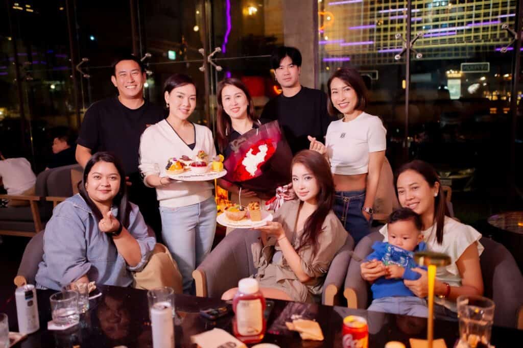ภาพถ่ายหมู่เพื่อนและครอบครัวกำลังฉลองวันเกิดหรืองานเลี้ยงโอกาสพิเศษ พร้อมเค้ก ของหวาน และช่อดอกไม้ที่ร้านอาหารจัดเลี้ยง Davin Cafe.