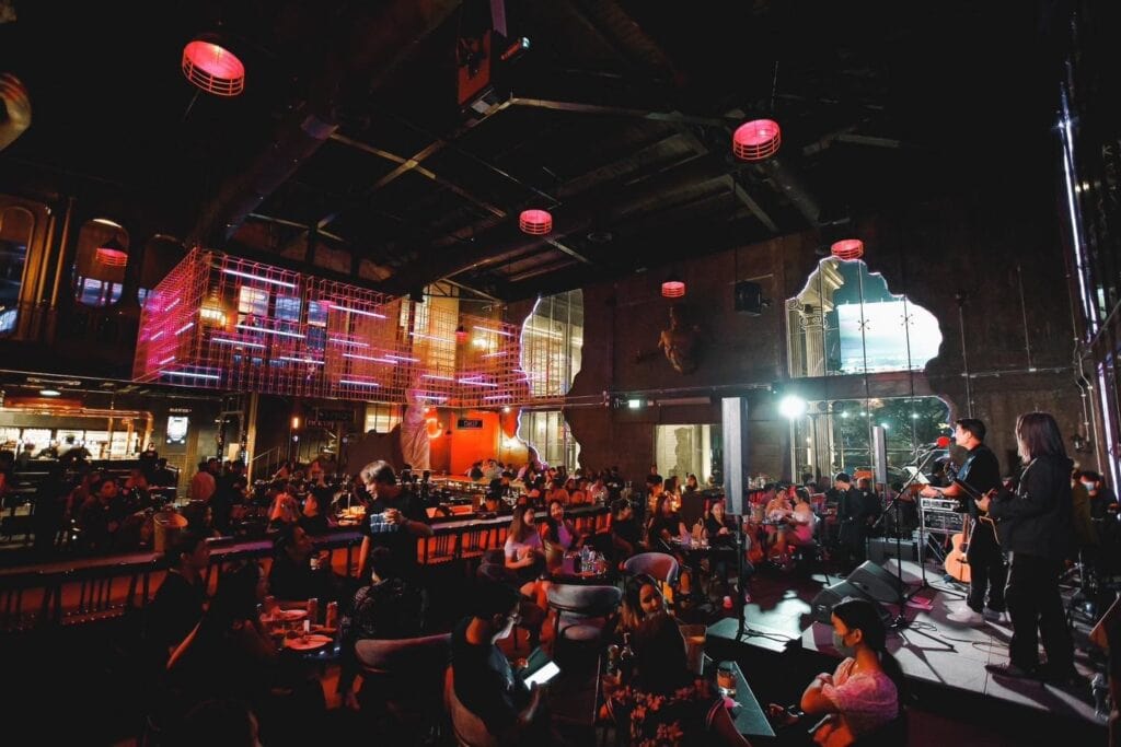 A New Year celebration venue featuring a live band performance in a spacious restaurant and bar setting, with guests enjoying drinks and music in a vibrant nighttime atmosphere, ideal for year-end parties, corporate events, and memorable New Year gatherings