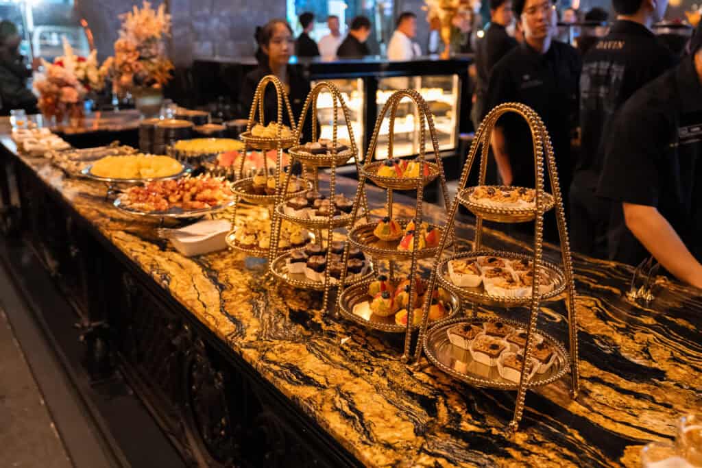 ไลน์ของหวานและผลไม้ที่จัดเตรียมสำหรับงานจัดเลี้ยงในร้านอาหาร โดยออกแบบการวางอาหารให้ดูเป็นระเบียบ เหมาะกับงานเลี้ยงบริษัทและอีเวนต์พิเศษ