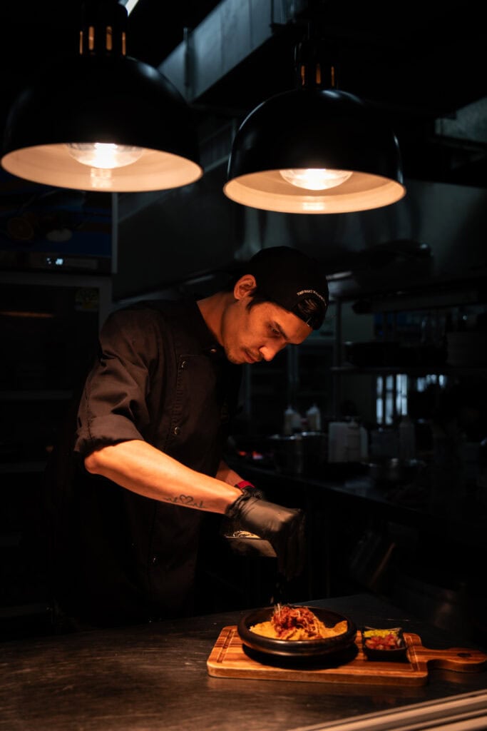 A chef carefully plating a signature dish at Davin Cafe’s open kitchen, highlighting a refined dinner experience where craftsmanship, precision, and culinary passion come together for an elevated evening dining moment.