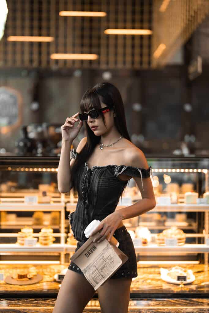 ลูกค้ายืนถ่ายภาพสไตล์แฟชั่นภายในร้านกาแฟเลียบด่วน รามอินทรา ท่ามกลางตู้โชว์เบเกอรี่และบรรยากาศพรีเมียมของ Davin Cafe ที่ผสานไลฟ์สไตล์ คาเฟ่ และมุมถ่ายรูปได้อย่างลงตัว