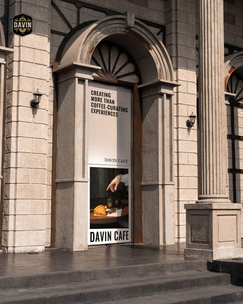 ซุ้มประตูโค้งด้านหน้า Davin Cafe บนถนนประดิษฐ์มนูธรรม พร้อมโปสเตอร์ “Creating More Than Coffee–Curating Experiences” สื่อภาพลักษณ์คาเฟ่และร้านอาหารจัดเลี้ยงที่ให้มากกว่ากาแฟในย่านประดิษฐ์มนูธรรม