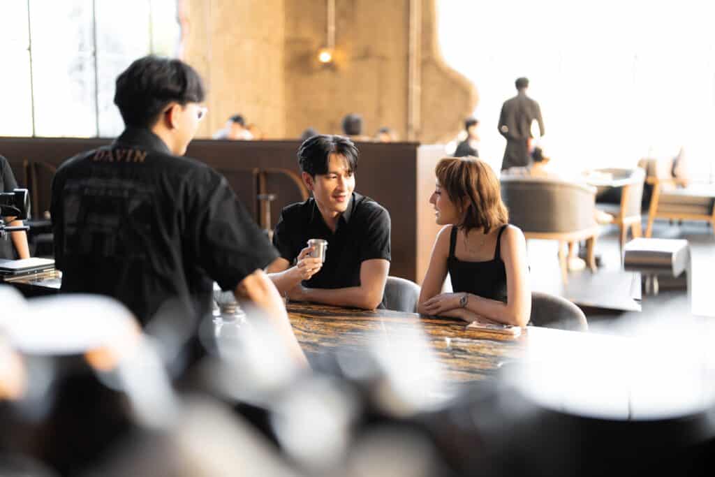 คู่ชายหญิงกำลังสนทนากันอย่างเป็นธรรมชาติในคาเฟ่บรรยากาศอบอุ่นสำหรับเดตแรก สะท้อนความผ่อนคลายและการสร้างความประทับใจครั้งแรก