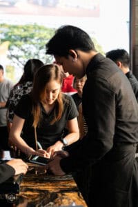 พนักงานเสิร์ฟรับออร์เดอร์ลูกค้าในร้านกาแฟ Davin Cafe บรรยากาศงานอีเวนต์สุดพิเศษ.