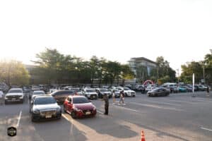 รถจอดในลานจอดรถของ Davin Cafe พร้อมผู้คนเดินชมและถ่ายภาพในบรรยากาศยามเย็น.