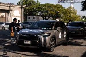 โตโยต้า ซีเอช-อาร์ คันสีดำจอดในลานจอดรถกลางแจ้งพร้อมผู้คนเดินผ่านในภาพ.