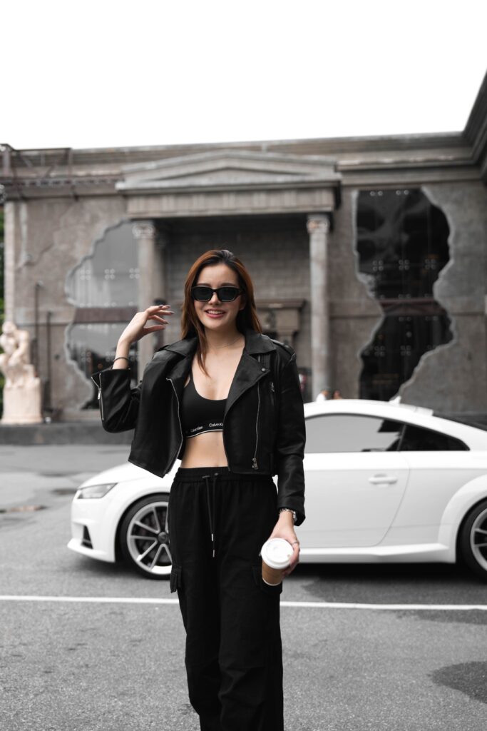 A stylish customer holding coffee in front of Davin Cafe’s European-inspired entrance with a luxury car backdrop, creating a fashion-forward urban café photo moment