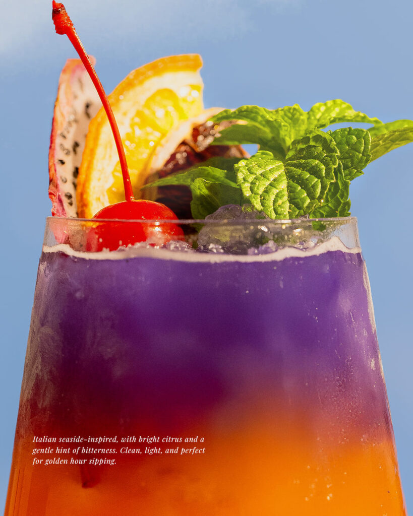 A premium summer menu main course 'Grilled snow fish in summer', featuring expertly grilled fish with vibrant orange sauce, creatively presented on a sand-themed display.