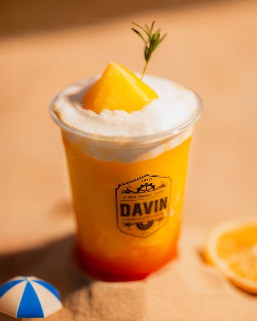 ภาพหน้าปกโปรโมตแคมเปญ "Savor the Sunshine: A refined taste of the season in every bite" ของ Davin Cafe ย่านประดิษฐ์มนูธรรม นำเสนอประสบการณ์ครบวงจรของเซ็ตเมนูซัมเมอร์ระดับพรีเมียม จัดวางอย่างสวยงามบนพื้นทรายริมชายหาดจำลอง