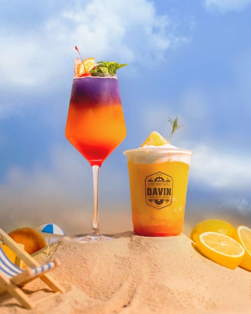 'Golden Hour', a signature summer cocktail with vibrant purple and orange layers, garnished with cherry and fresh mint, showcasing Davin Cafe's mixology expertise.