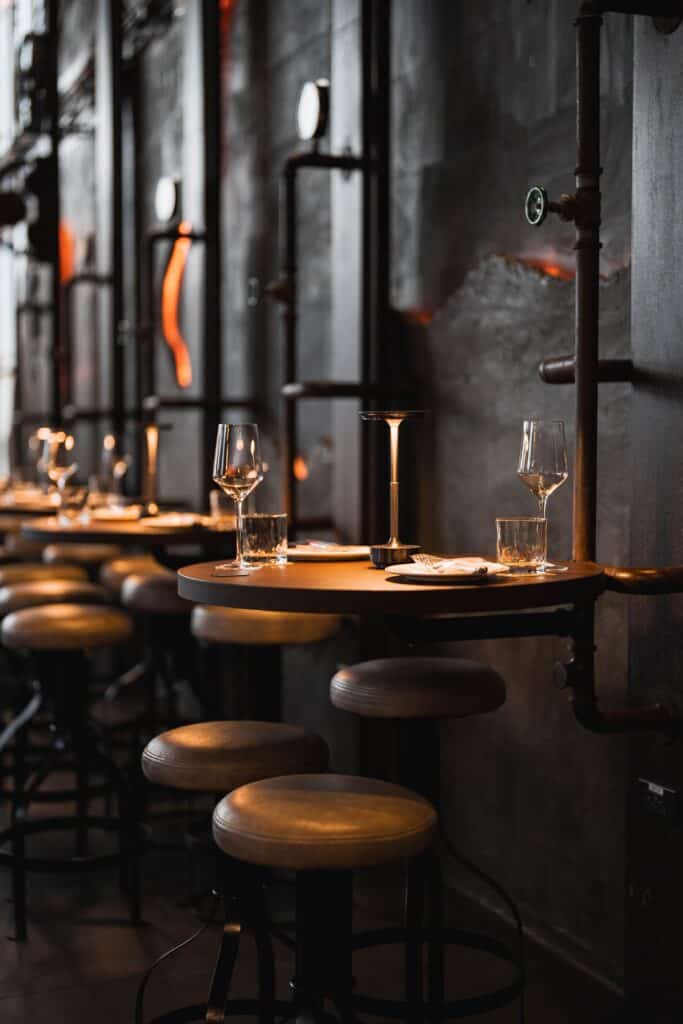 มุมนั่งบาร์ภายใน Davin Cafe ที่จัดโต๊ะและเก้าอี้อย่างมีสไตล์ พร้อมแสงไฟโทนอุ่นและดีไซน์ผนังแบบยุโรปผสมอินดัสเทรียล เหมาะสำหรับคนที่มองหาคาเฟ่ สไตล์ยุโรป ที่ให้บรรยากาศผ่อนคลายและดูพรีเมียม