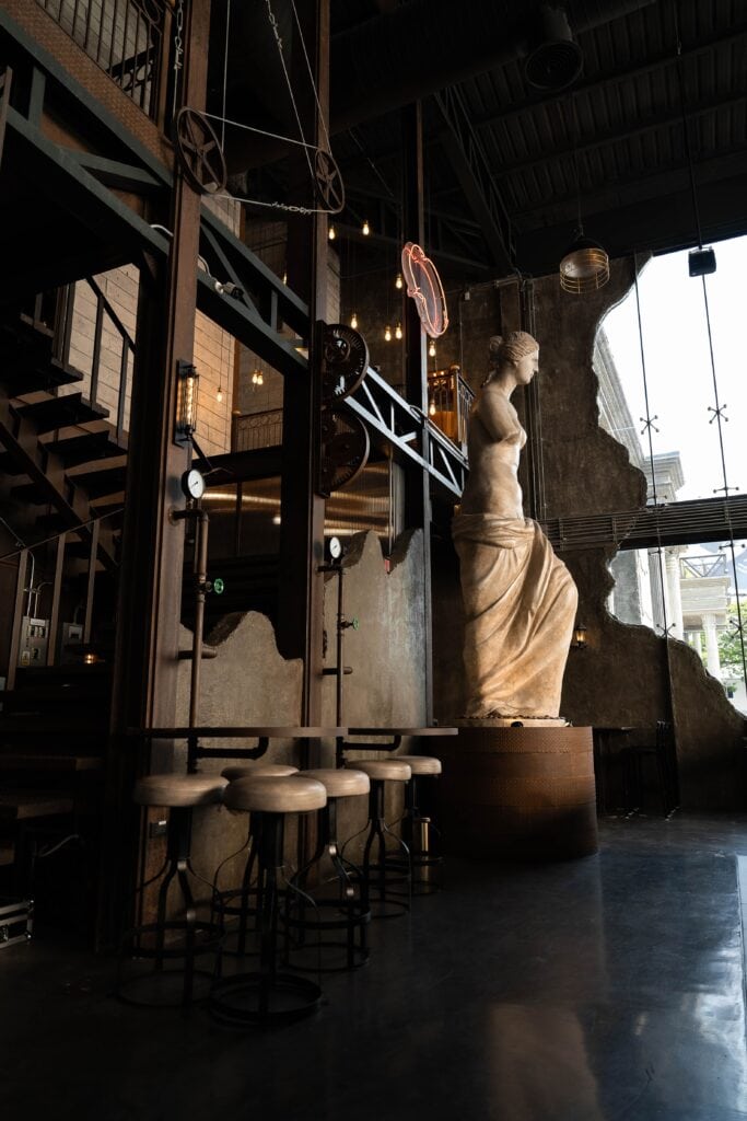 A striking interior at Davin Cafe featuring European-style sculpture combined with industrial steel structures and warm lighting, creating a distinctive and luxurious European-inspired café atmosphere