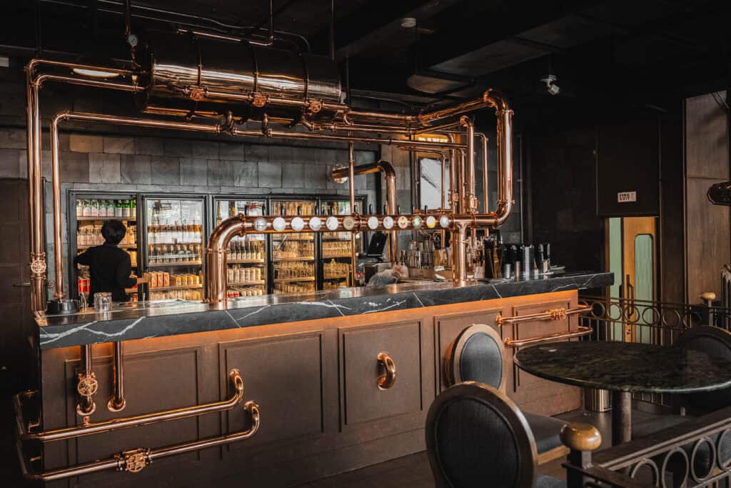 An industrial-style copper bar counter at Davin Cafe, offering a stylish and relaxed setting during the Songkran season, perfect for enjoying drinks and escaping the Bangkok heat