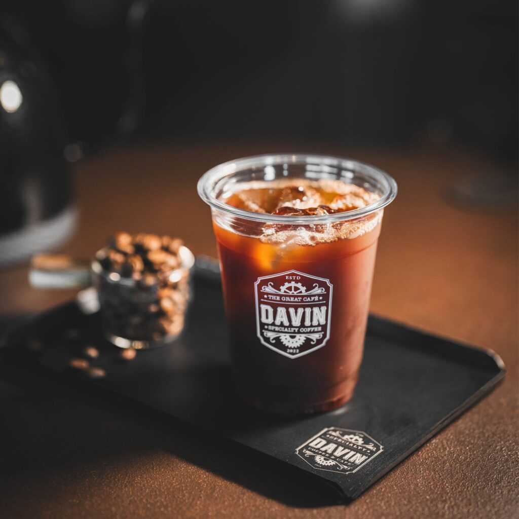 Iced light roast coffee served in a clear cup at Davin Cafe, highlighting a clean and refreshing profile with bright fruity notes, placed alongside coffee beans to reflect origin and flavor clarity