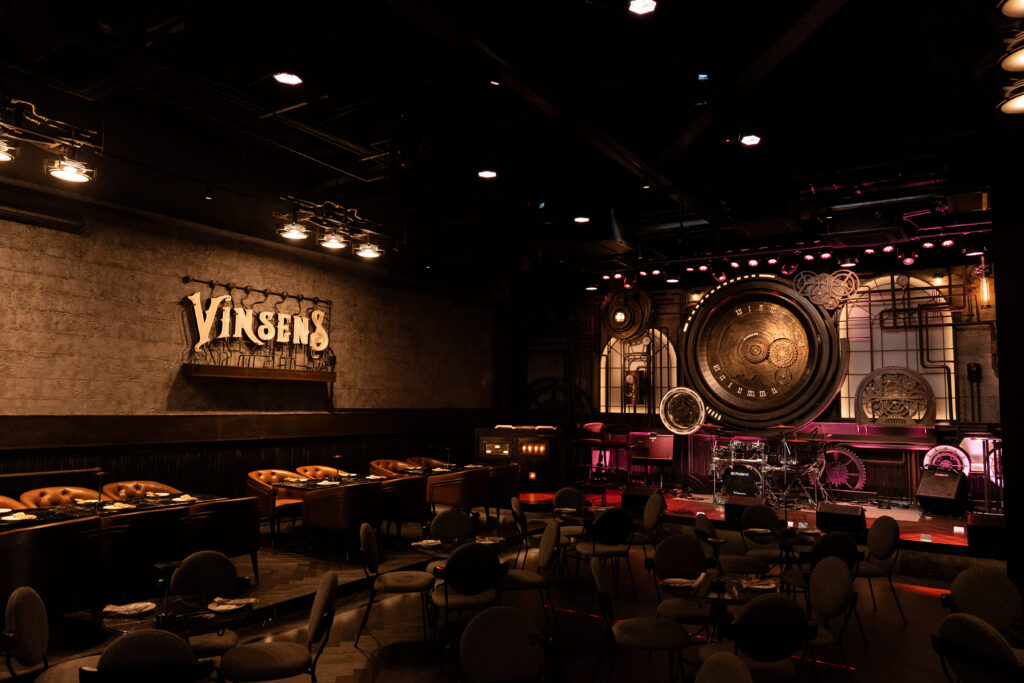 ภาพมุมกว้างภายในร้าน Vinsens ร้านนั่งชิล รามอินทรา โดดเด่นด้วยเวทีดนตรีสดดีไซน์สไตล์อินดัสเทรียล บรรยากาศหรูแต่ผ่อนคลาย เหมาะสำหรับนั่งดื่มและสังสรรค์ยามค่ำคืน