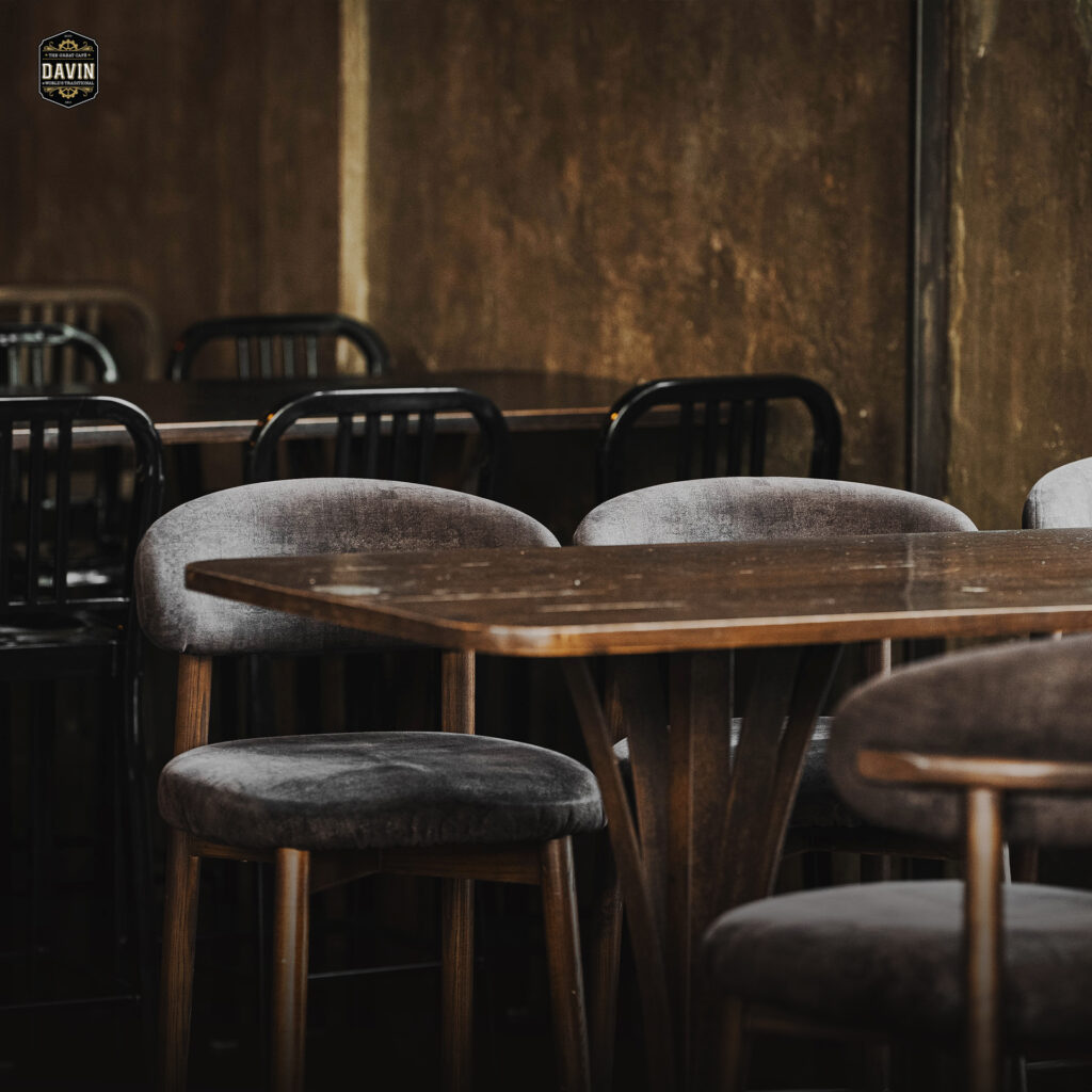Warm wooden dining table and elegant seating inside Davin Cafe, a Bangkok cafe and restaurant space designed for private meals, small celebrations, and refined group dining in a relaxed modern atmosphere.