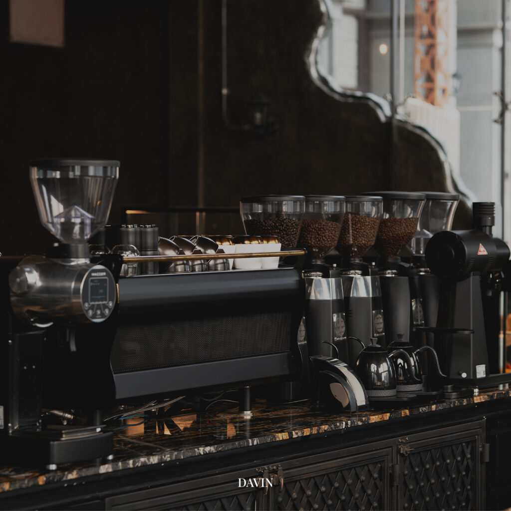 มุมบาร์กาแฟของ Davin Cafe ที่มีเครื่องชงเอสเปรสโซ่ เครื่องบด และโถเมล็ดกาแฟเรียงพร้อมใช้งาน สะท้อนความใส่ใจในการเตรียมกาแฟ คั่วกลางให้ได้รสชาติสมดุล กลิ่นหอมชัด และคุณภาพสม่ำเสมอในทุกแก้ว
