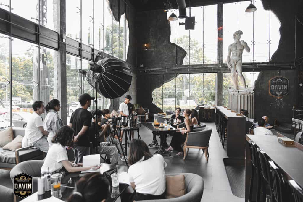 ทีมโปรดักชันถ่ายทำคอนเทนต์และงานวิดีโอภายใน DAVIN CAFE สตูดิโอคาเฟ่ดีไซน์หรูเพดานสูง พร้อมแสงธรรมชาติและมุมถ่ายภาพระดับมืออาชีพ เหมาะสำหรับงานถ่ายแบบ โฆษณา พอดแคสต์ และครีเอทีฟโปรดักชันในกรุงเทพ
