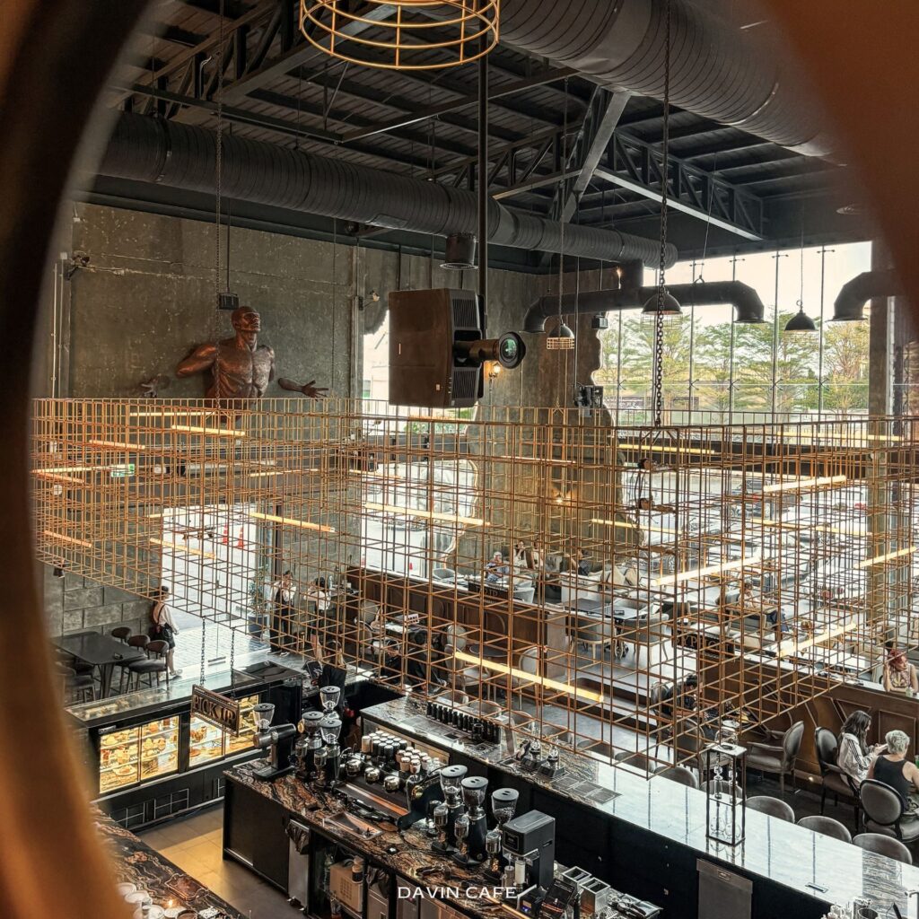 High-angle interior view of DAVIN CAFE, a luxury industrial-style cafe near me on Ram Intra Expressway Bangkok, featuring specialty coffee, iconic architectural design, aesthetic photo spots, and a premium lifestyle cafe atmosphere