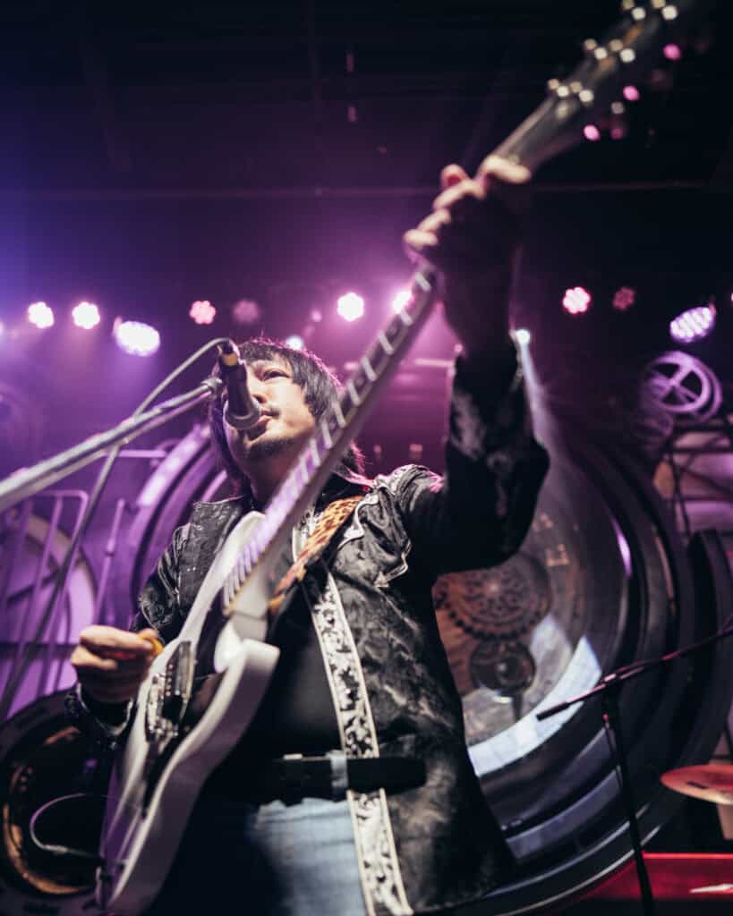 Close-up live music performance at Davin Cafe with an artist singing and playing guitar under concert lighting, highlighting a Bangkok fan meet venue designed for mini concerts, artist events, and intimate fan experiences
