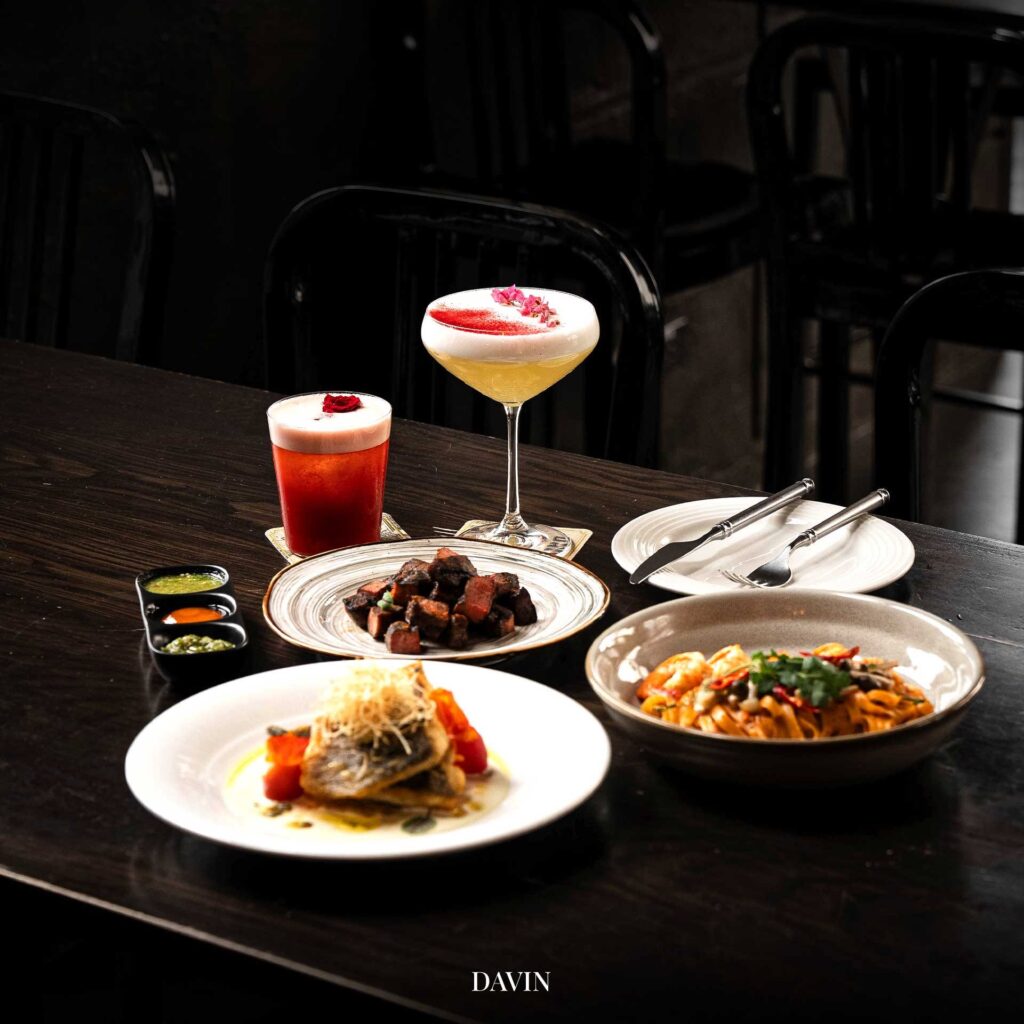 ชุดอาหารและเครื่องดื่มบนโต๊ะของ Davin Cafe ที่มีทั้งเมนูคาว พาสต้า สเต๊ก และเครื่องดื่มซิกเนเจอร์ สื่อถึงประสบการณ์คาเฟ่พรีเมียมที่สามารถจับคู่กาแฟ เข้มกับอาหารได้อย่างลงตัว เหมาะสำหรับมื้อพิเศษและการนั่งดื่มด่ำบรรยากาศของร้าน