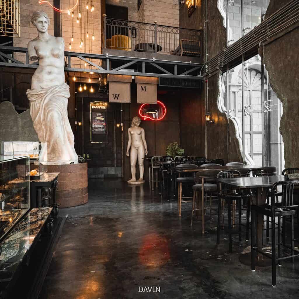ภายใน DAVIN CAFE ร้านอาหารบรรยากาศดี กรุงเทพ โดดเด่นด้วยดีไซน์ Industrial Luxury เพดานสูง ประติมากรรมสไตล์ยุโรป และพื้นที่รับประทานอาหารโปร่งโล่ง เหมาะสำหรับมื้อพิเศษ นัดพบ และการใช้เวลาคุณภาพในกรุงเทพ