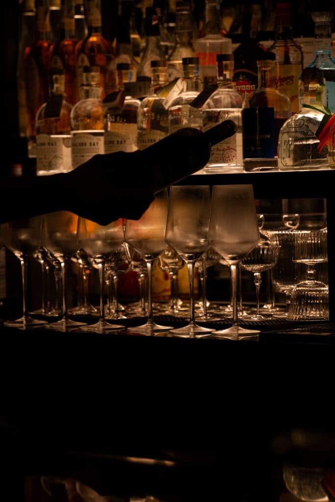 Wine glasses and premium bottles displayed behind the bar at VINSENS, capturing a stylish chill bar in Bangkok with warm lighting, intimate atmosphere, and refined details for relaxed drinks, conversations, and memorable nights out.