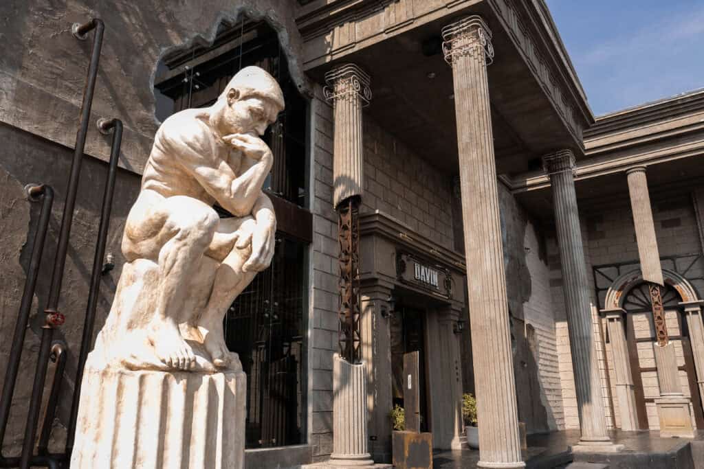 Exterior view of Davin Cafe in Ramintra with European-inspired columns and a large sculptural landmark, presenting a distinctive work-friendly cafe destination for guests seeking a stylish place to work, relax, and enjoy coffee in Bangkok.