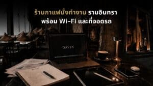 ภาพปกบทความร้านกาแฟนั่งทำงานรามอินทรา ของ Davin Cafe แสดงโต๊ะทำงานพร้อมแล็ปท็อป สมุดโน้ต กาแฟ และบรรยากาศคาเฟ่โทนอบอุ่น เหมาะสำหรับคนที่มองหาพื้นที่นั่งทำงานพร้อม Wi-Fi ที่จอดรถ และมุมสงบสำหรับโฟกัสงานระหว่างวัน