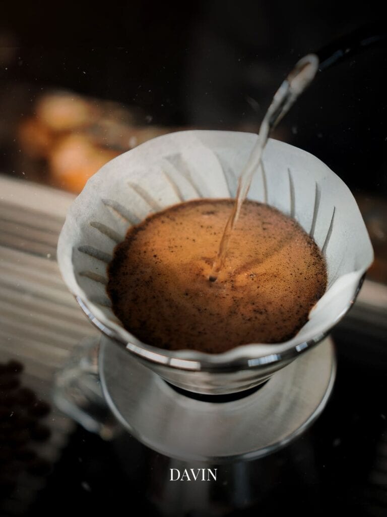 Close-up of the V60 pour-over blooming process, demonstrating the optimal brewing method for light roast coffee to enhance floral aromas and natural sweetness.