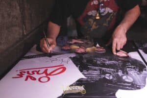A legendary musician signing a poster for his supporters during an exclusive event at a fan meeting venue in Bangkok.