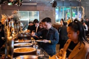 Event attendees picking delicious food from a well-arranged buffet line at a luxurious corporate party venue in Bangkok.