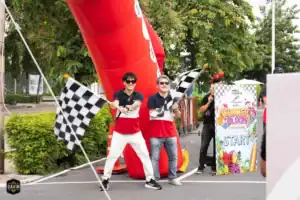Men enthusiastically waving checkered flags at a car rally hosted at Davin Cafe's outdoor event space rental in Bangkok.