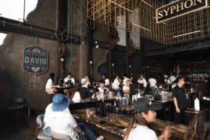 Event attendees enjoying a coffee break and networking around the large elegant bar at a seminar venue in Bangkok.
