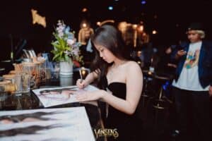 A beautiful female celebrity signing autographs for her dedicated supporters at a luxurious fan meeting venue in Bangkok.
