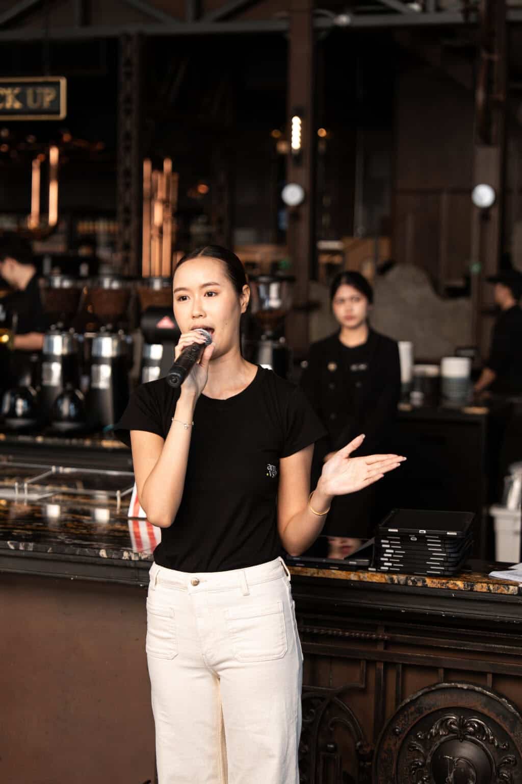 A female presenter speaking confidently into a microphone during a corporate event at our seminar venue in Bangkok.