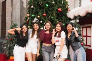 A group of friends posing in front of a beautifully decorated Christmas tree at Davin Cafe, a versatile event space rental in Bangkok.