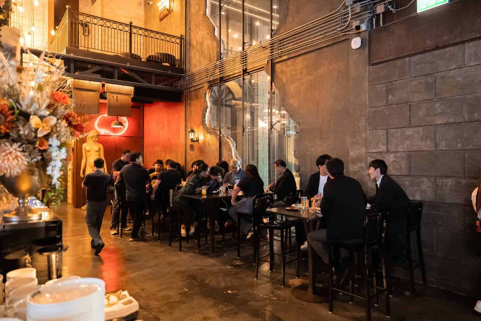 Guests mingling and enjoying drinks in the stylish reception area of a unique corporate party venue in Bangkok.
