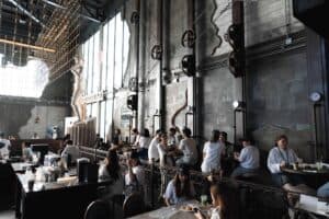 Event attendees chatting and relaxing in the high-ceiling hall decorated with industrial elements at our corporate party venue in Bangkok.