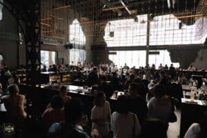 A large crowd of professionals networking and socializing in the grand hall of a popular corporate party venue in Bangkok.
