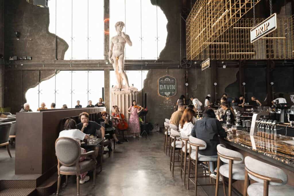 Guests enjoying live classical music by the David statue inside Davin Cafe, a unique meetup space in Bangkok.