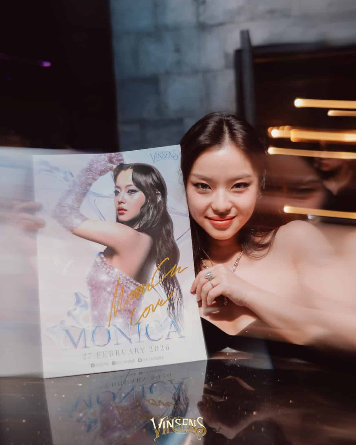 A guest holding a Monica poster at a Vinsens event hosted at Davin Cafe, a popular event space rental in Bangkok.