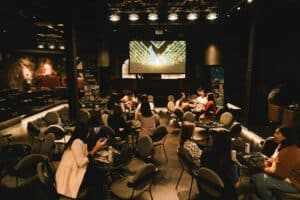 Attendees seated at round tables networking before a presentation at a well-equipped seminar venue in Bangkok.