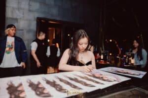 A famous singer attentively signing posters for her fans during a meet and greet at a popular fan meeting venue in Bangkok.