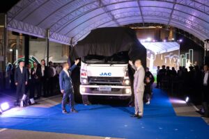 Executives unveiling a new JAC electric truck under a large marquee at Davin Cafe, a fully equipped event space rental in Bangkok.